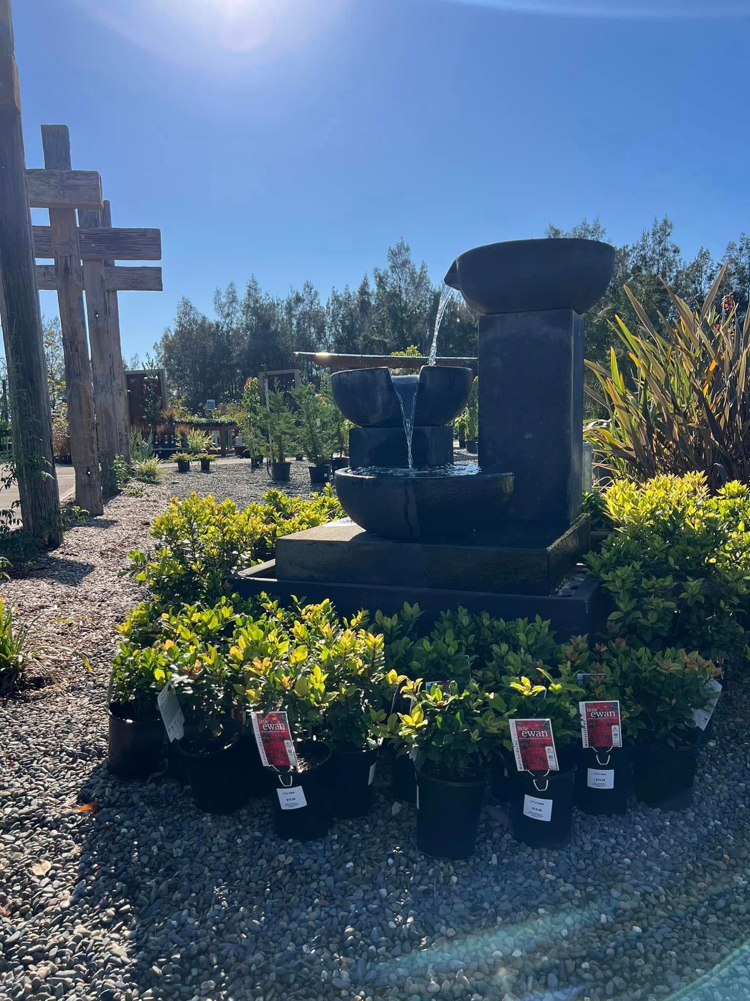 Stone Fountain with Cascading Water, Surrounded by Potted Green Plants — Port Landscape Supplies in Port Macquarie, NSW