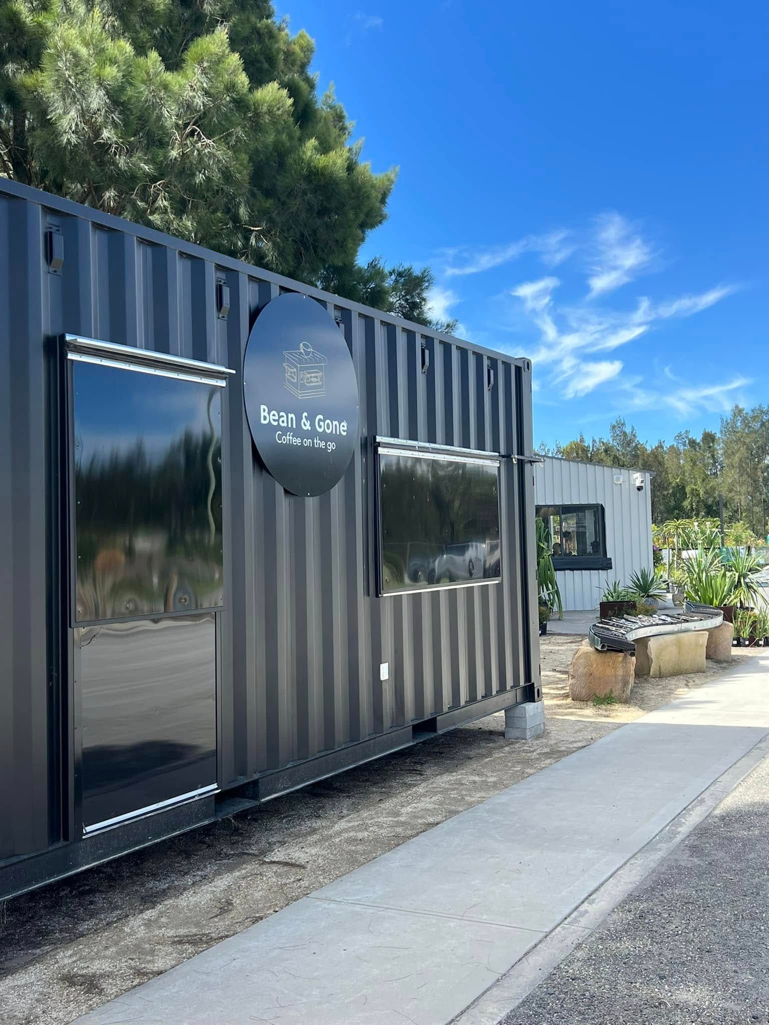 Dark Grey Shipping Container Building With Black Windows and Signage Under — Port Landscape Supplies in Port Macquarie, NSW