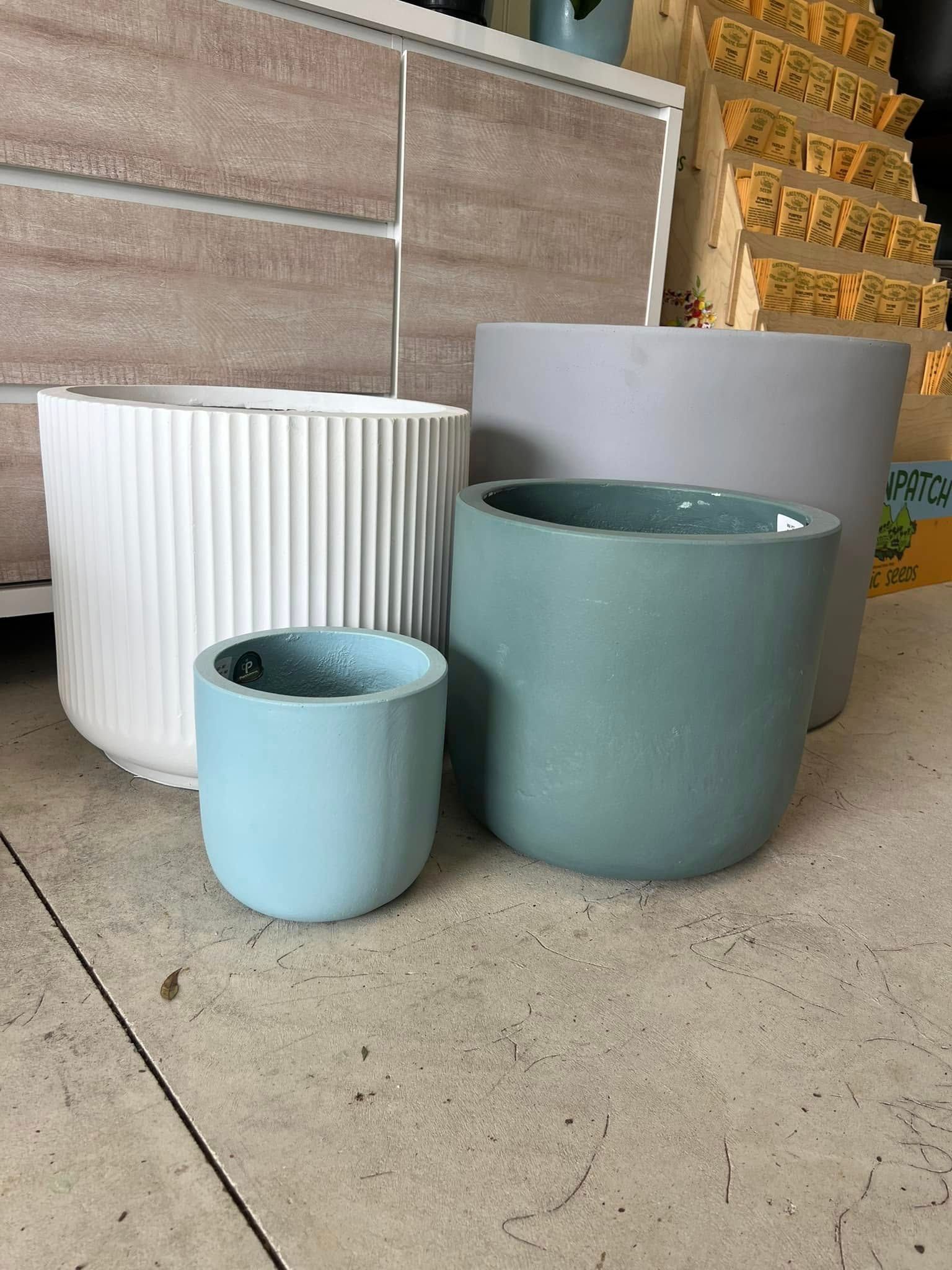 Four Different Coloured, Modern Ceramic Planters Sitting on A Concrete Floor — Port Landscape Supplies in Port Macquarie, NSW