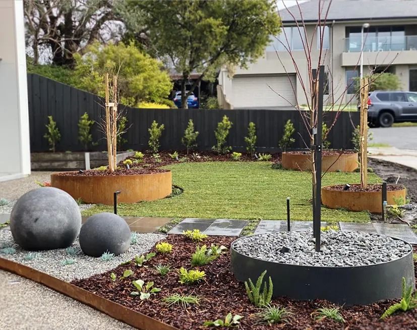 Front Yard Landscaping With Trees in Circular Planters — Port Landscape Supplies in Port Macquarie, NSW