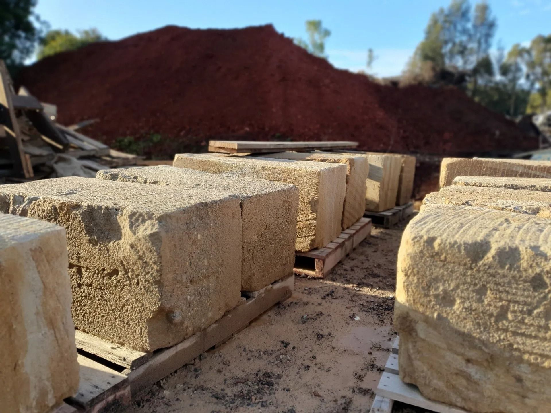 Sandstone Blocks Stacked On Pallets With A Pile Of Red Dirt — Port Landscape Supplies in Port Macquarie, NSW