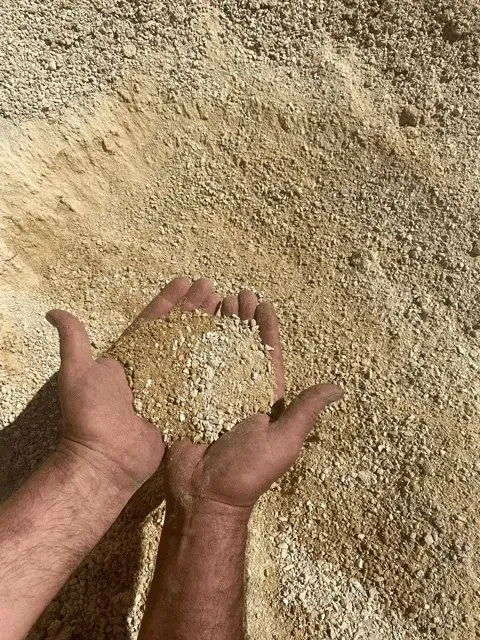 Person's Hands Holding a Pile of Tan and Beige Aggregate — Port Landscape Supplies in Port Macquarie, NSW