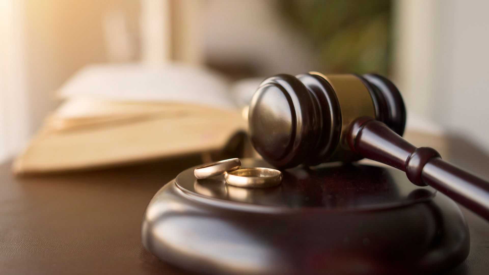 Judge’s gavel beside wedding rings symbolizing divorce proceedings.