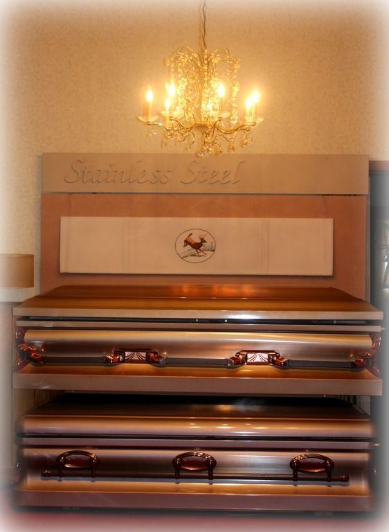 Two stainless steel caskets stacked. Above, a sign reads 