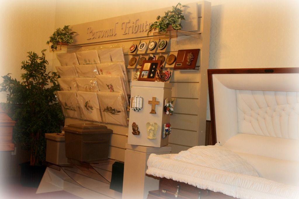 A funeral home display with memorial items, including a casket, cards, and crosses.