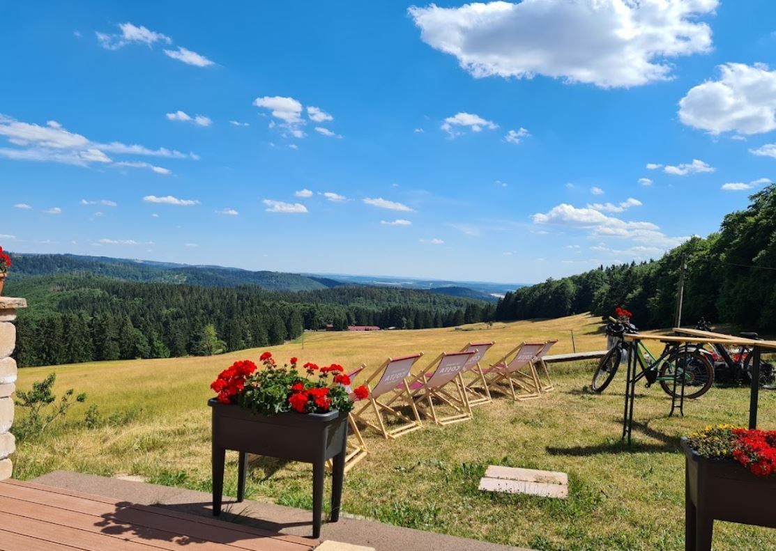 A view of a field with chairs and a bicycle on a patio.