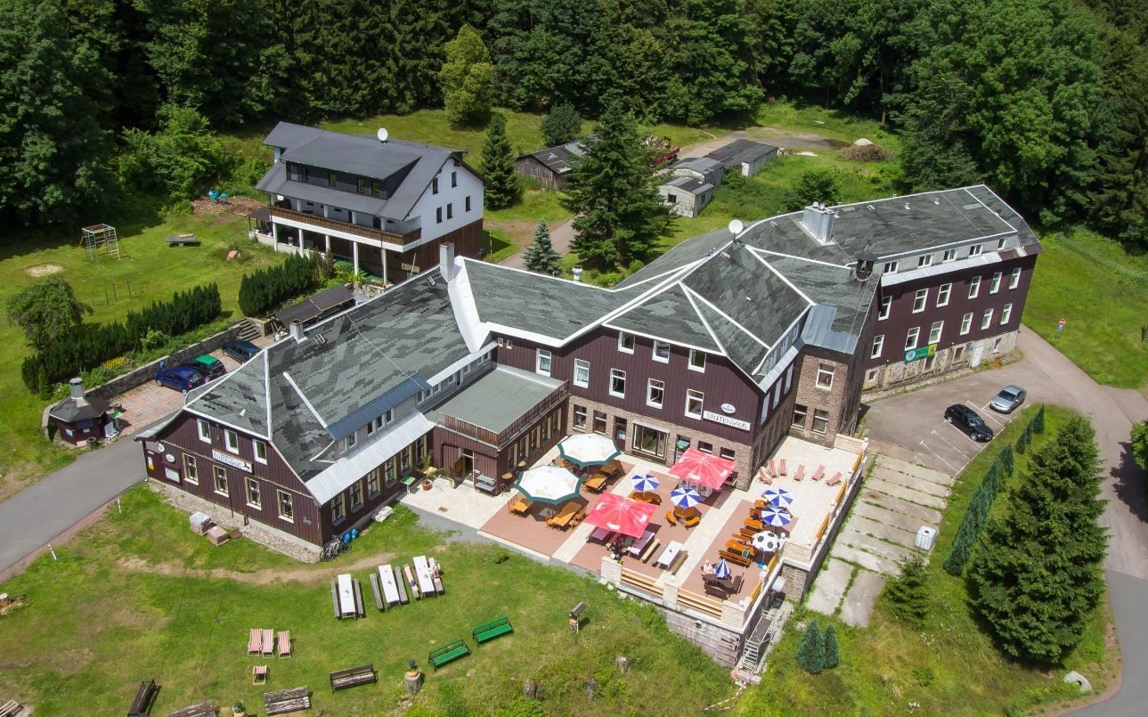 An aerial view of a large building with tables and chairs in front of it.