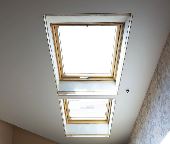 Due lucernari in un soffitto bianco, uno più grande e uno più piccolo, con cornici in legno.