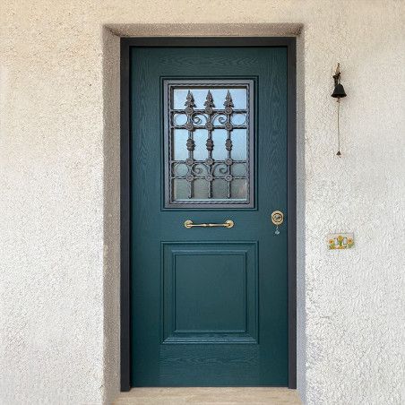 Porta d'ingresso color verde acqua con finestra decorativa in vetro e maniglia in ottone, incastonata in una parete di stucco chiaro.