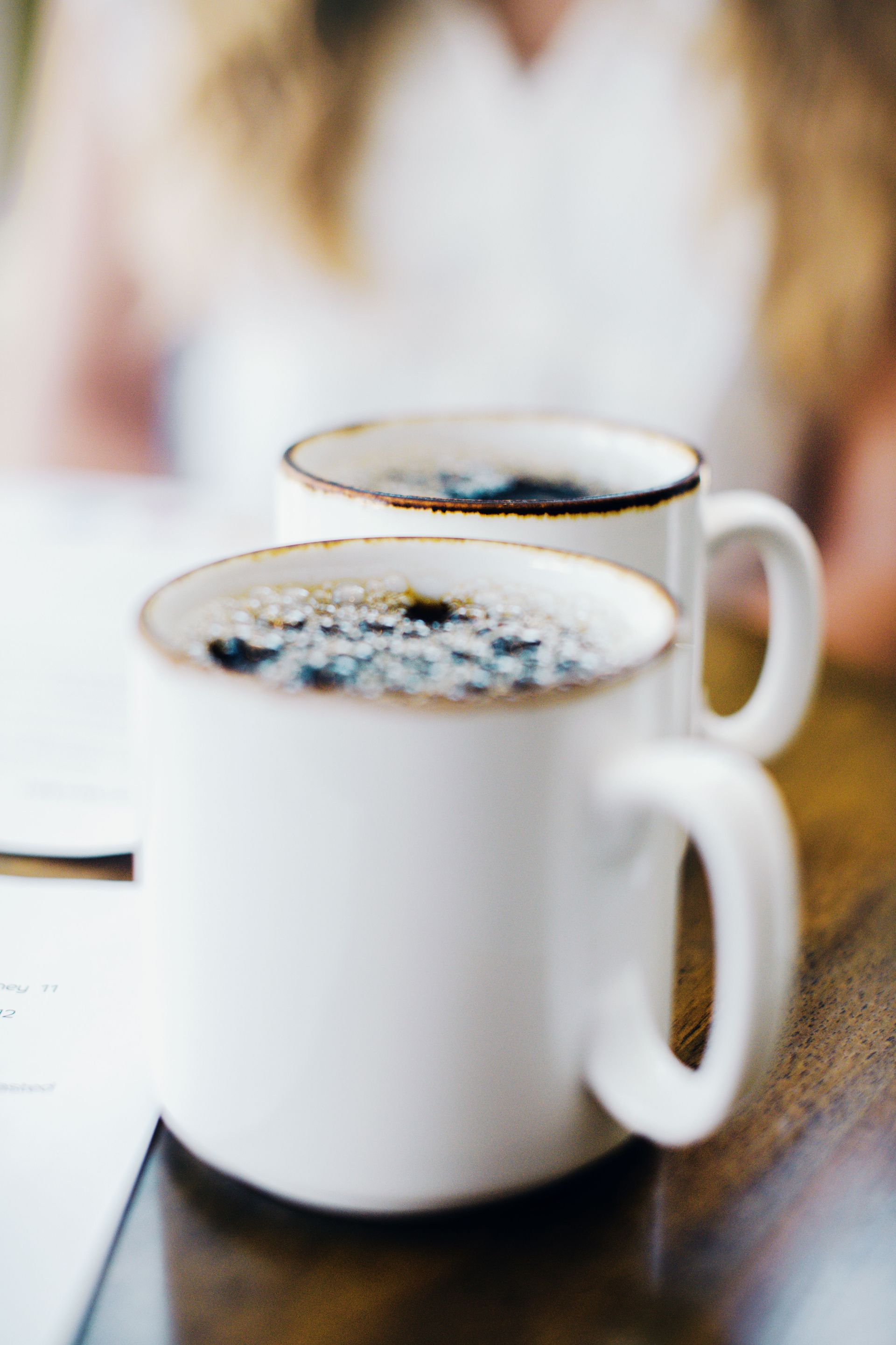 Two white mugs of coffee on a wooden surface — illustrative photo