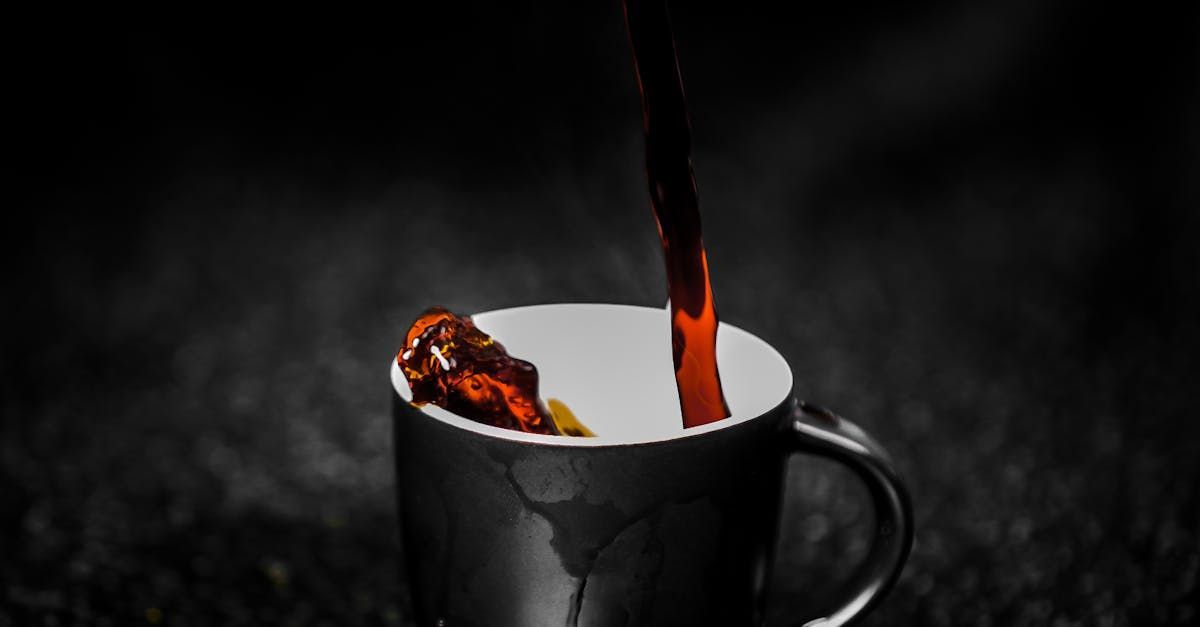 Coffee pouring into a black cup on a dark surface — illustrative photo