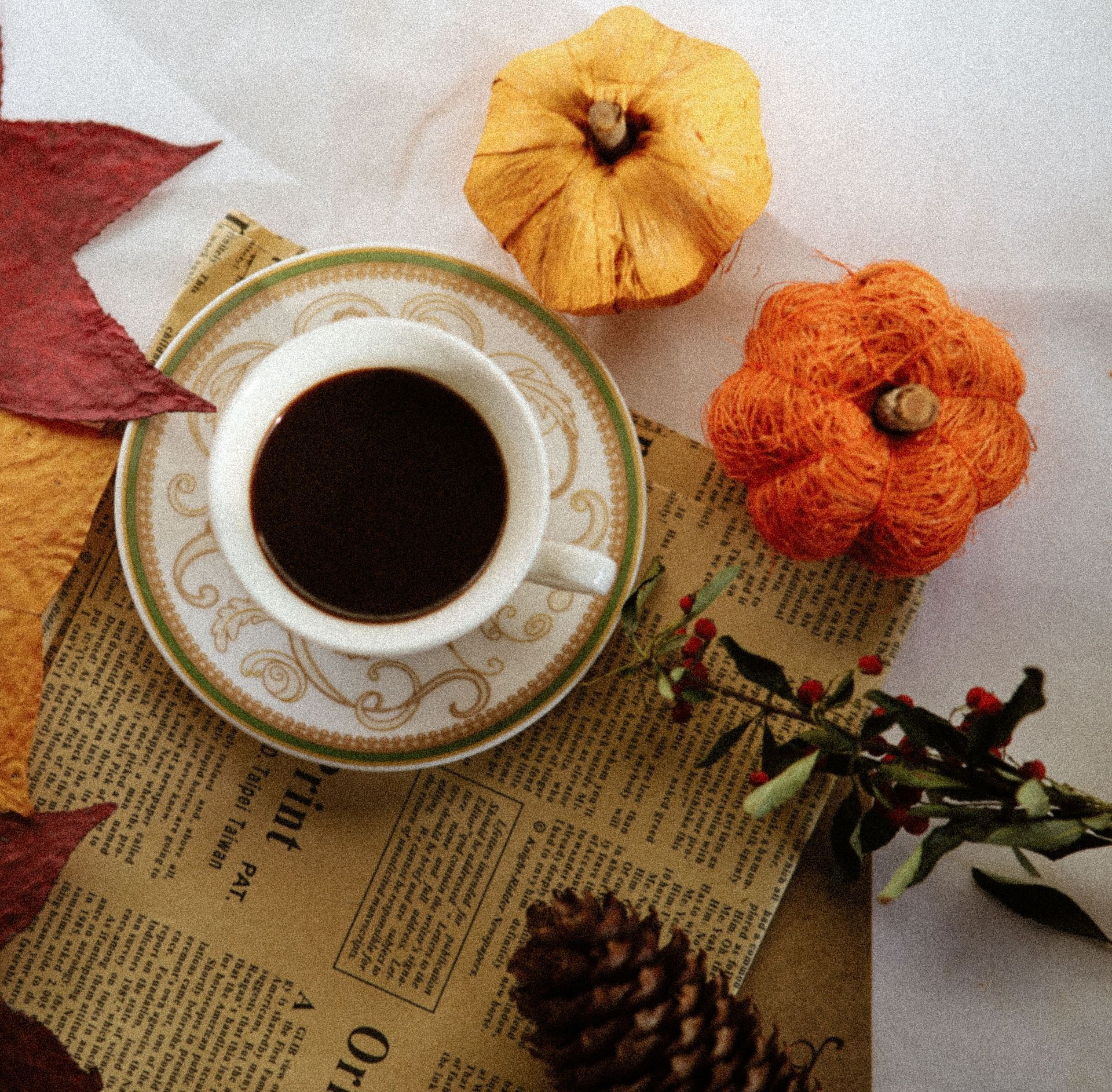 Cup of black coffee beside small orange pumpkins and autumn leaves — illustrative seasonal photo