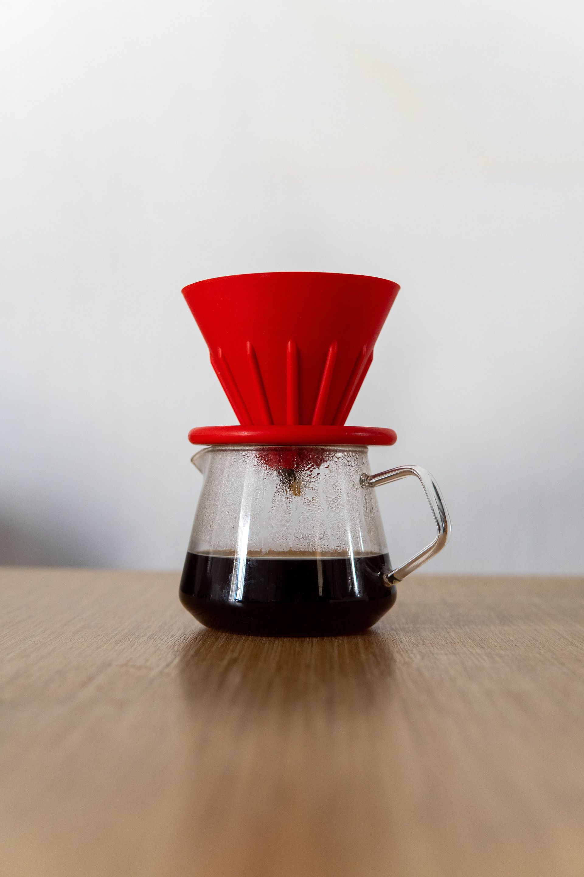 Red pour-over dripper on a glass server of black coffee — illustrative brewing photo
