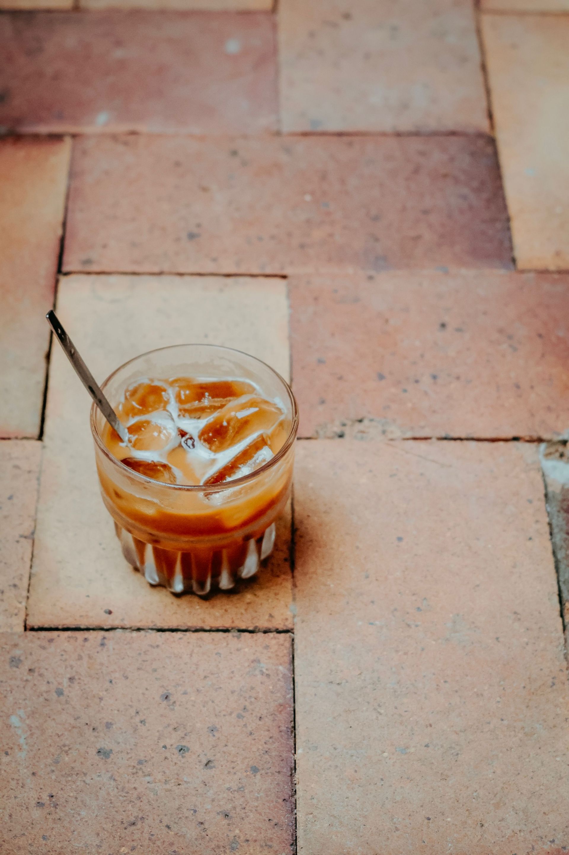 Glass of iced coffee against a warm brick backdrop — illustrative photo