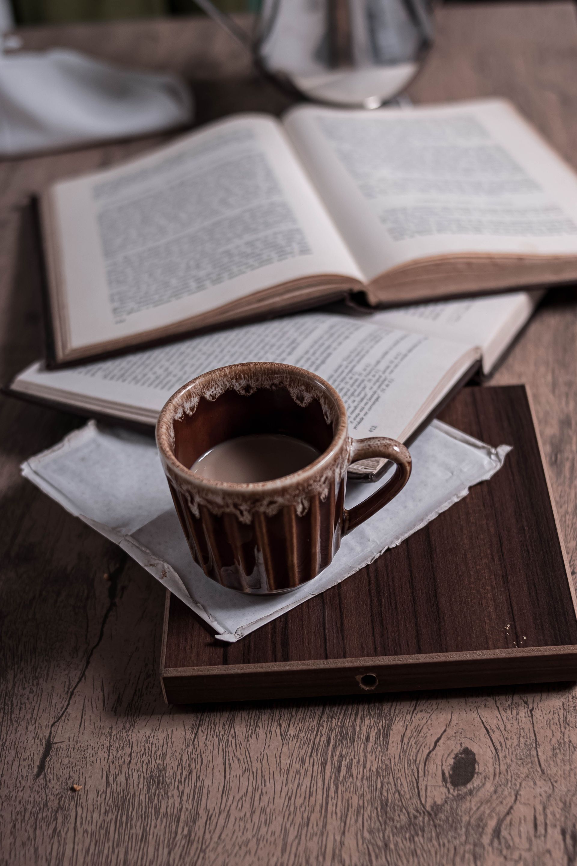 Ceramic mug of black coffee on a wooden tray beside an open book — illustrative photo
