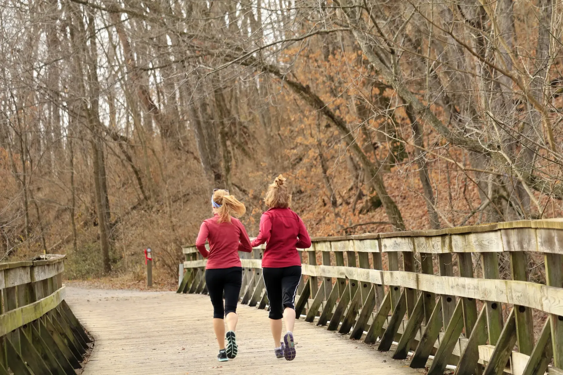 Two women running along a path wearing red shirts and black leggings