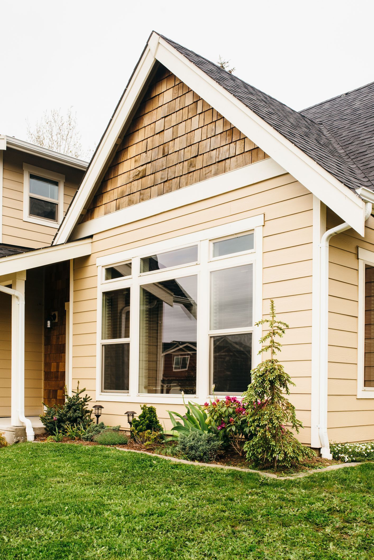 Tan house with large windows, brown roof, and green lawn. Tan house with large windows, brown roof, and green lawn.