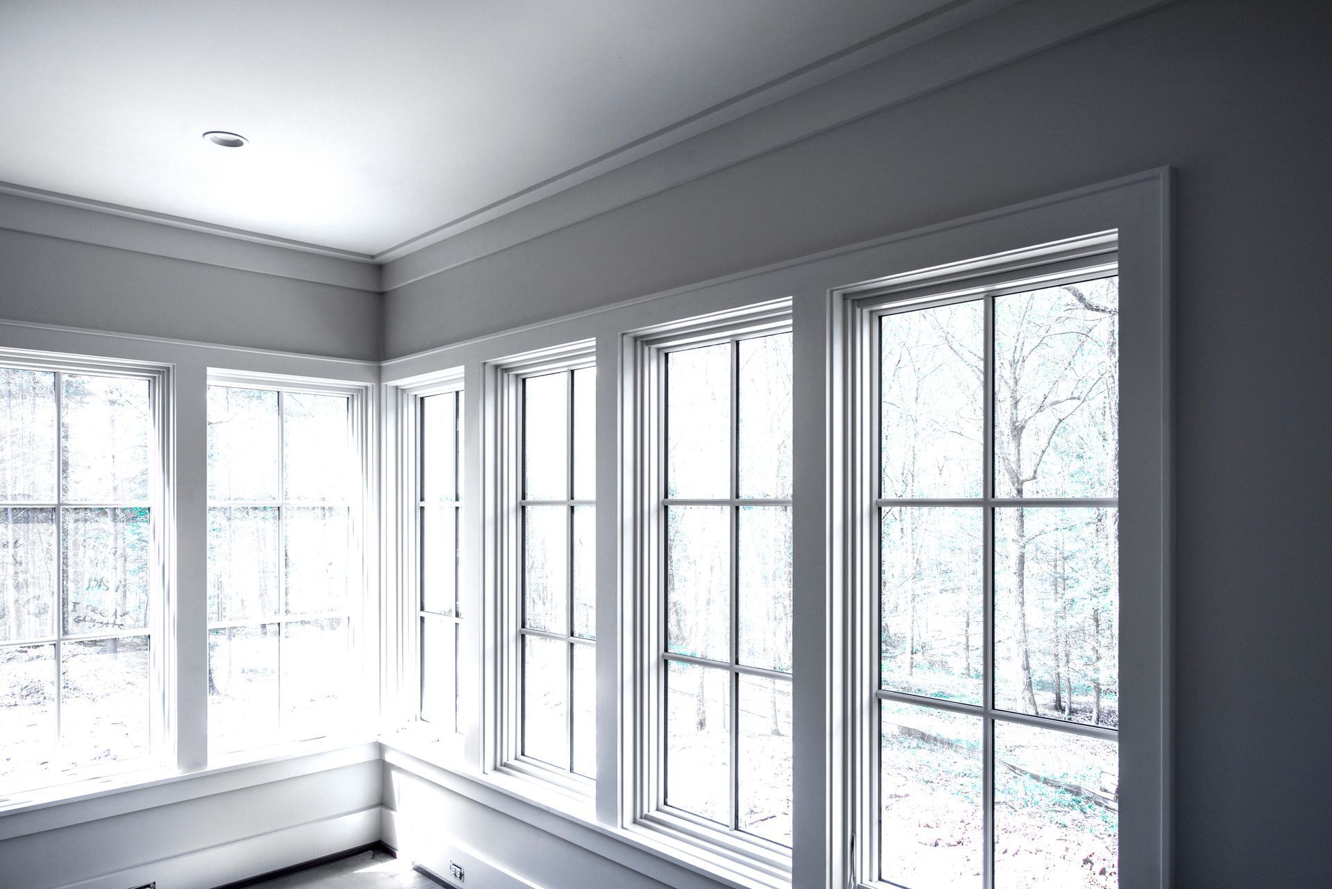 Three white-framed windows, angled in a corner, with a view of a blurry, light-filled outdoor scene. Three white-framed windows, angled in a corner, with a view of a blurry, light-filled outdoor scene.