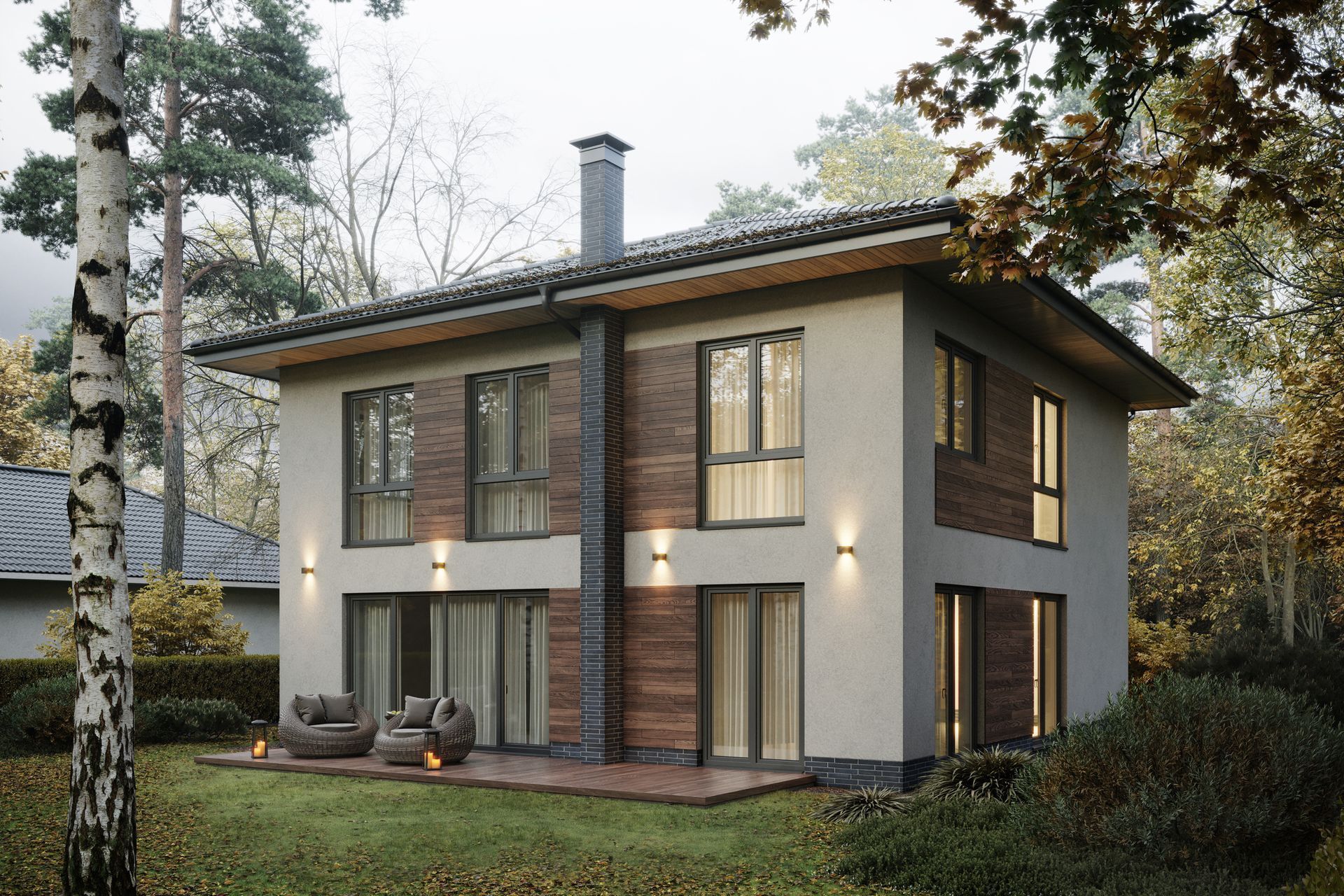 Two-story modern house with brown and gray facade, set in a wooded area with lawn and patio.