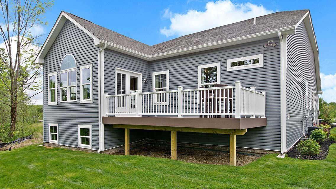 White-framed sliding glass window on a light blue house exterior, reflecting outdoor scene with snow.