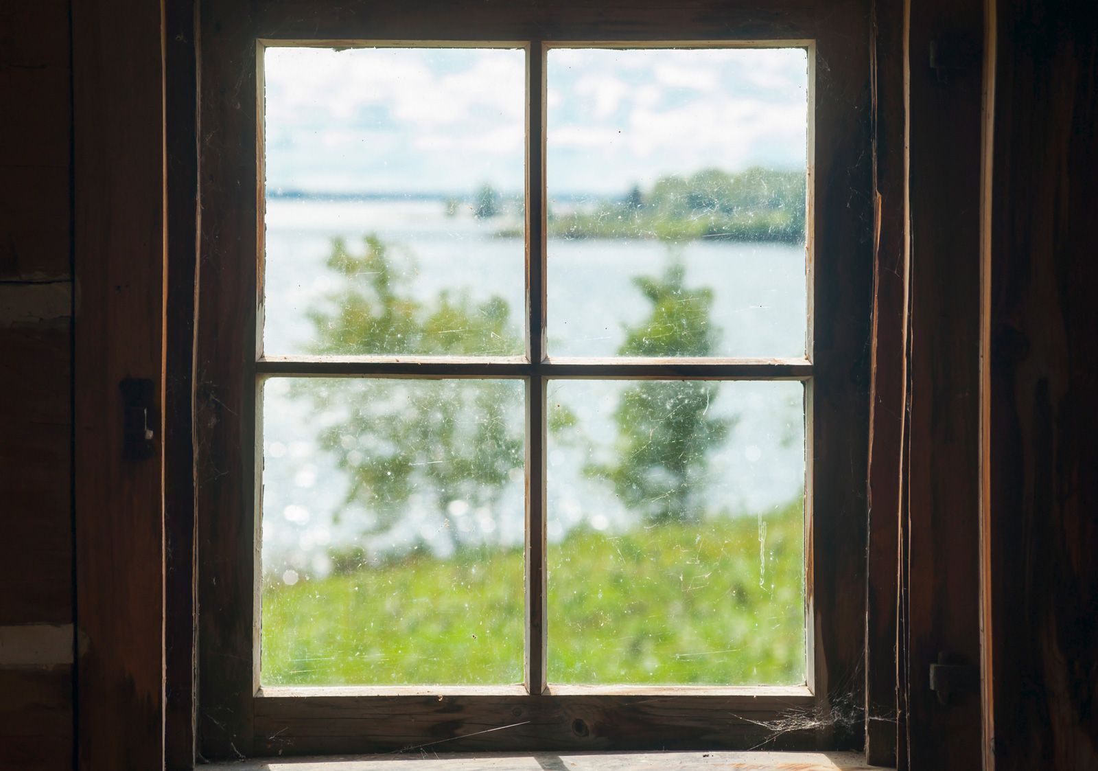 Wooden-framed window view of lake and trees on a sunny day. Wooden-framed window view of lake and trees on a sunny day.
