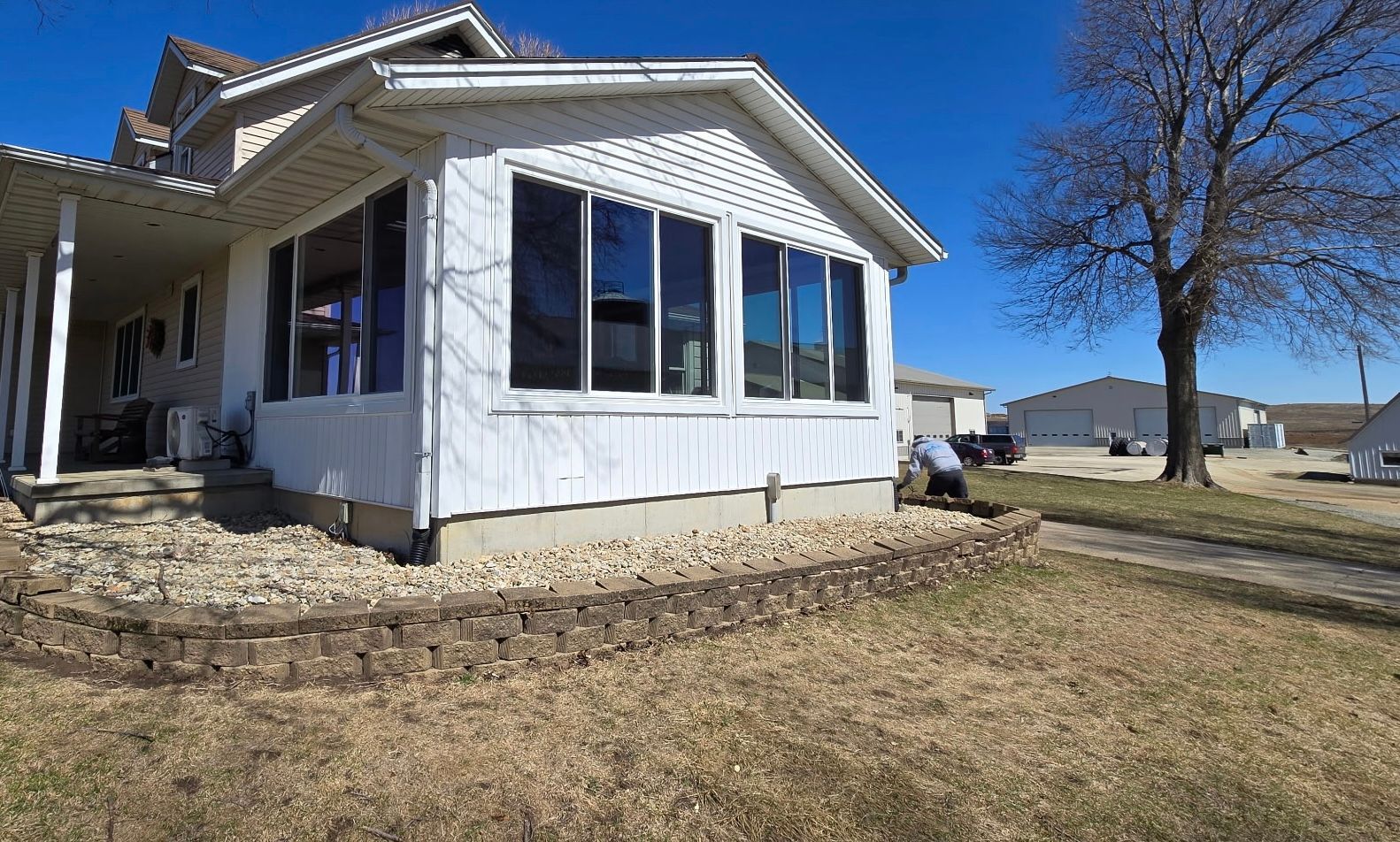 White house with a screened-in porch, sitting on a rock foundation, under a blue sky. White house with a screened-in porch, sitting on a rock foundation, under a blue sky.