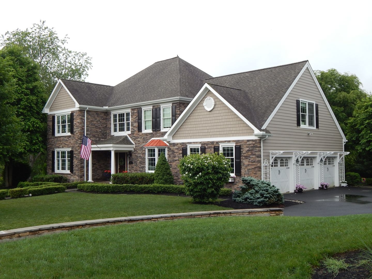 Two-story brick house with a dark roof, white trim, and a three-car garage on a well-manicured lawn. Two-story brick house with a dark roof, white trim, and a three-car garage on a well-manicured lawn.