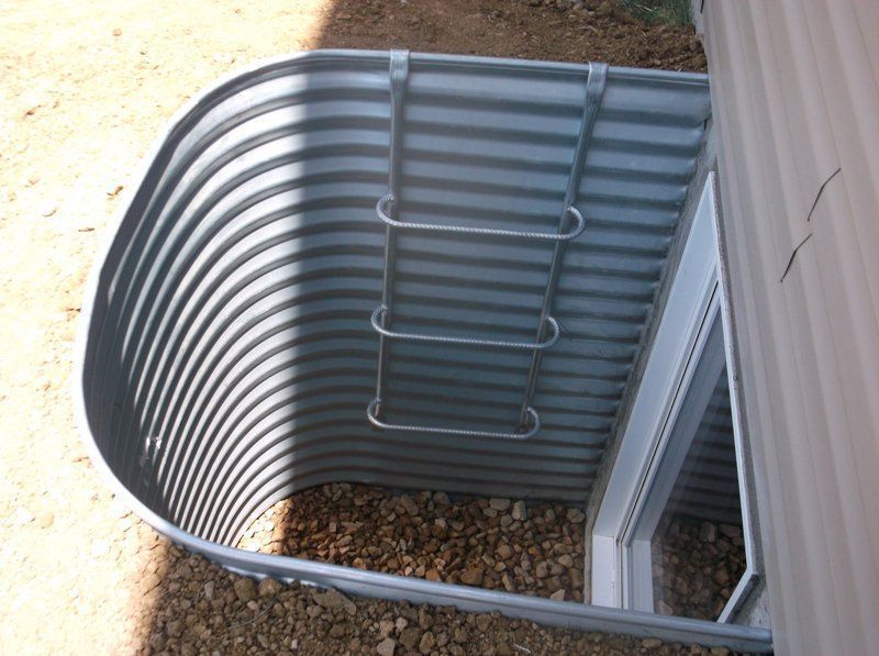 Metal window well with ladder and gravel.