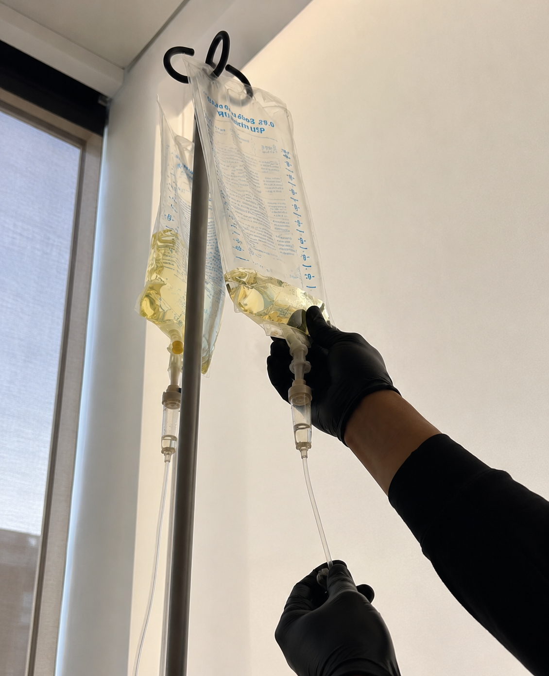 Healthcare professional preparing an IV fluid bag for intravenous hydration, illustrating the difference between IV hydration and oral hydration.