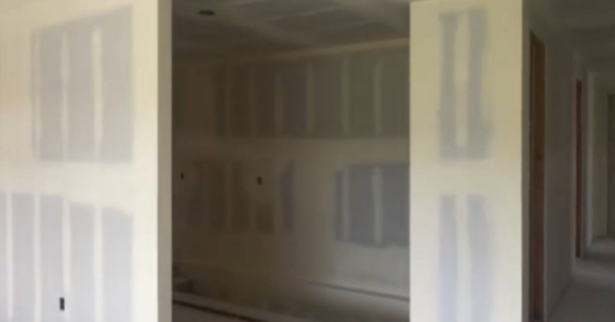 An interior space under construction featuring drywall installation, framed openings, and unfinished walls.