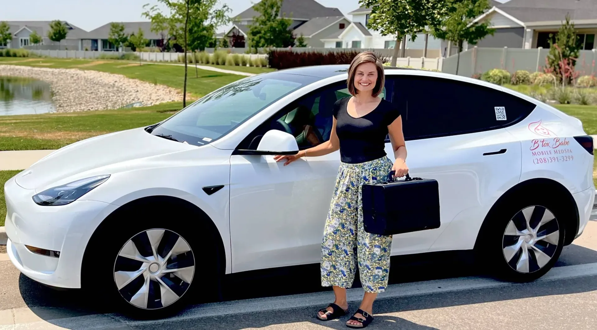 A woman is standing in front of a white tesla model y.