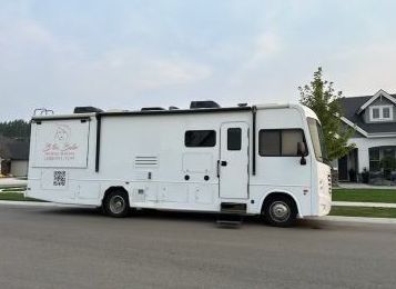 A white rv is parked on the side of the road in front of a house.