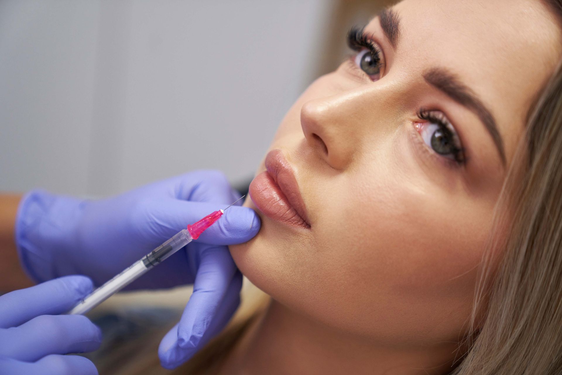 A woman is getting a botox injection in her lips.