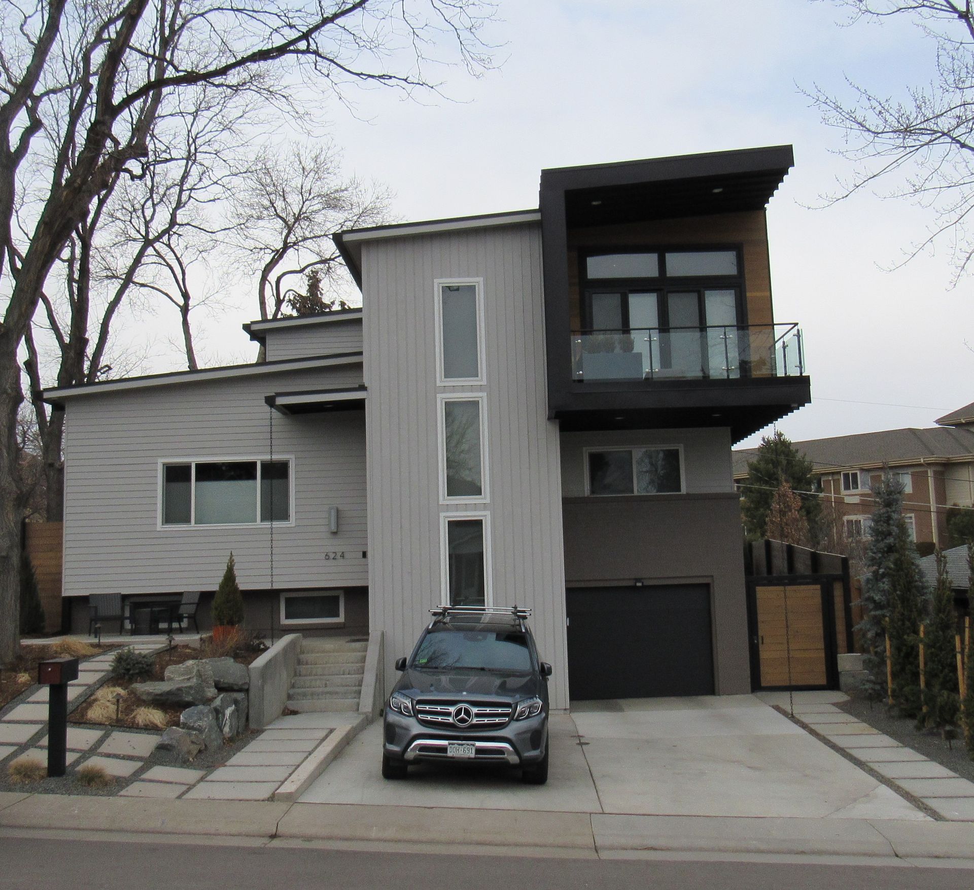 Modern two-story house with gray siding, black accents, and a car parked in the driveway.