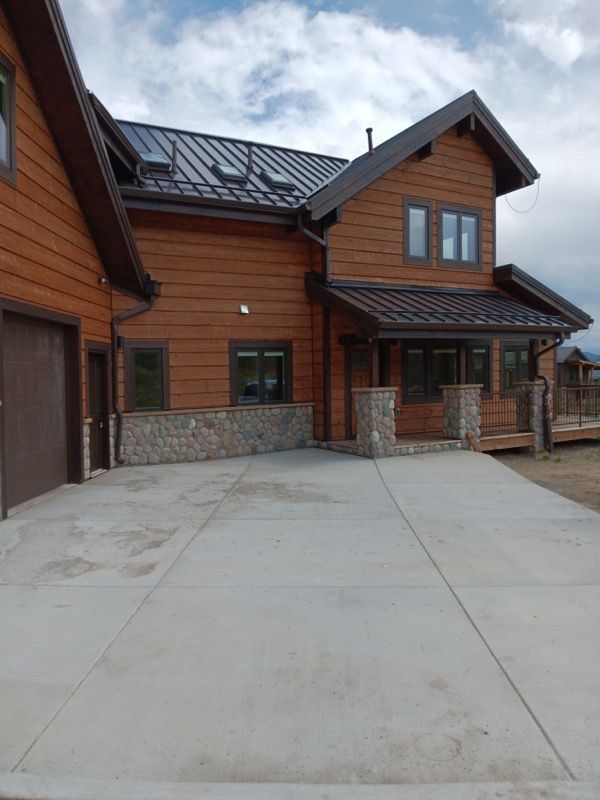 Two-story wood-sided house with a concrete driveway, a garage, and a stone foundation.