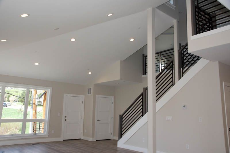 Interior view of a modern home with a staircase, high ceilings, and recessed lighting.