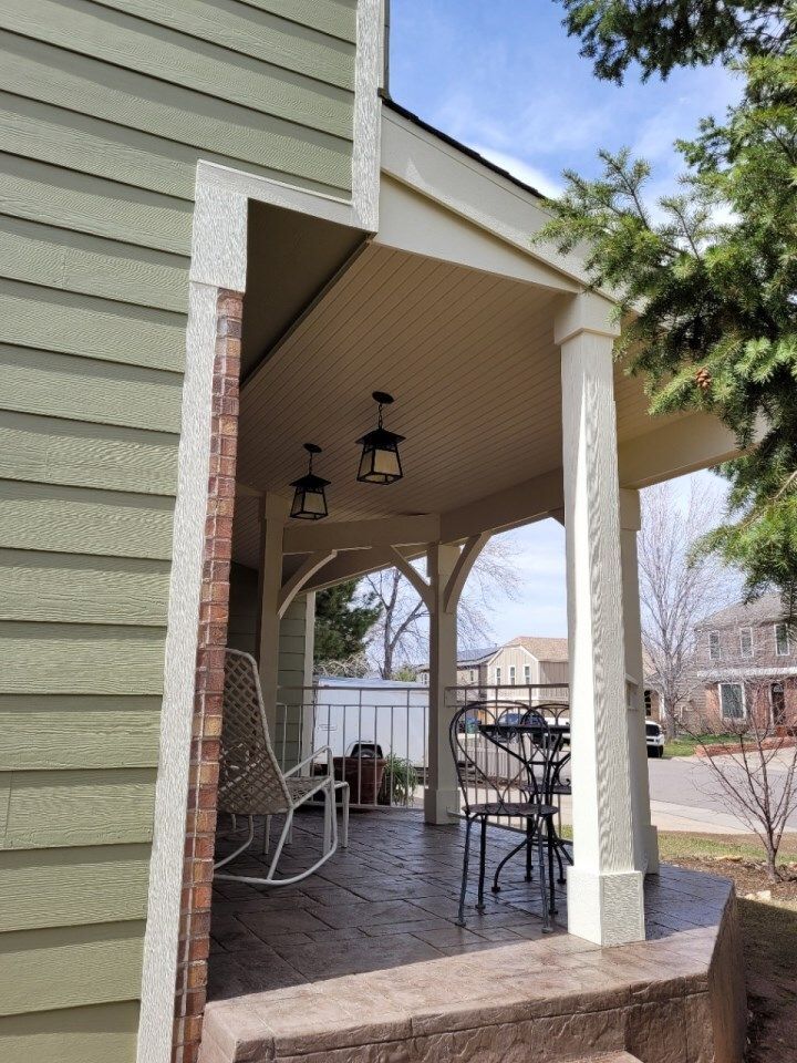 Covered porch with a stamped concrete floor, columns, and outdoor furniture.