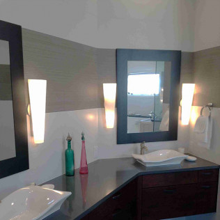 Bathroom with mirrors, sinks, and sconce lighting. Gray, brown, and white color scheme.