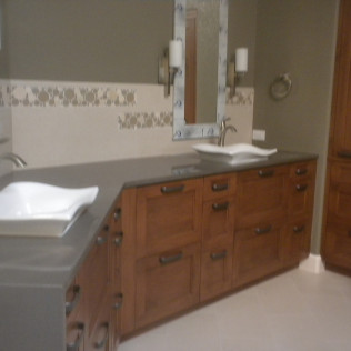 Bathroom with wood vanity, gray countertop, and two vessel sinks, with a mirror and sconces.