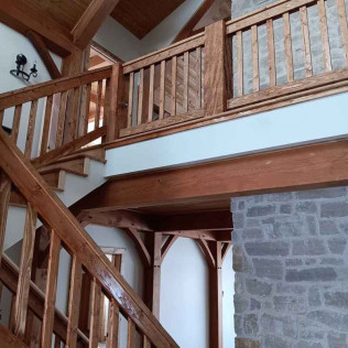 Wooden staircase and balcony with stone fireplace; interior view.