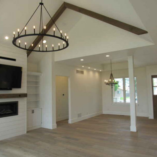 A modern living room with hardwood floors, a fireplace, and two chandeliers.