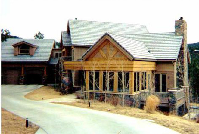 Rustic home with a stone chimney, wood accents, and a garage on a hillside.