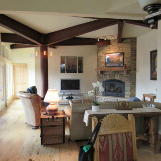 Living room with fireplace, exposed beams, wood floors, and seating areas.