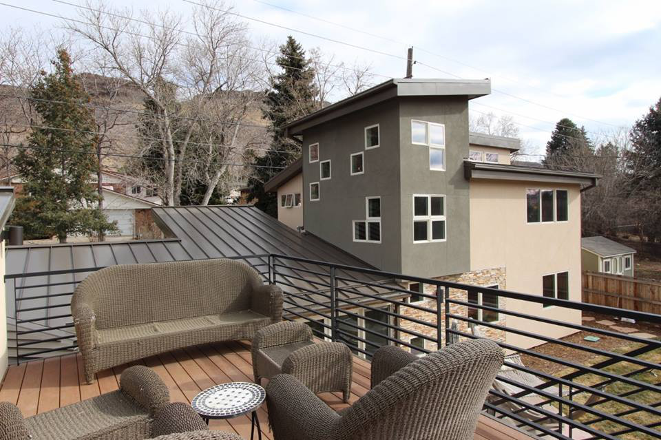 Outdoor patio with wicker furniture and modern house in the background.
