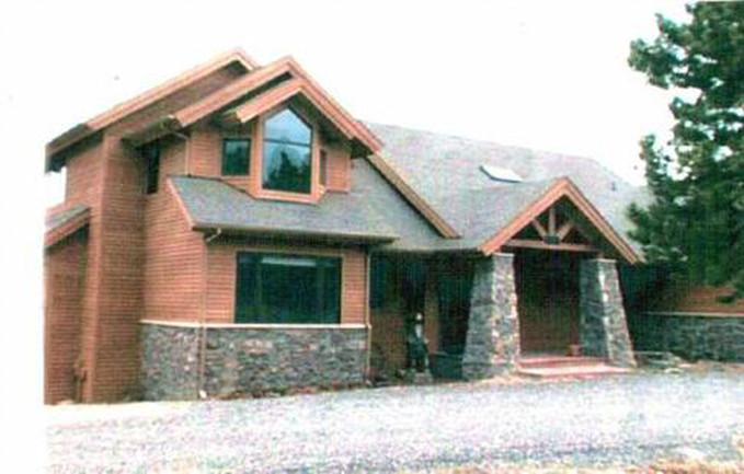 Brown wood house with stone accents, an arched entrance, and a gable roof.