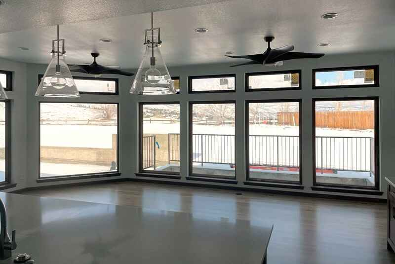 Interior view with large windows overlooking a snowy landscape, two ceiling fans, and pendant lights.
