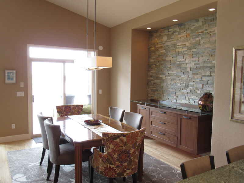 Dining room with a wooden table, chairs, and a stone accent wall.