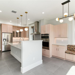 Modern kitchen with light wood cabinets, stainless steel appliances, and a large island.