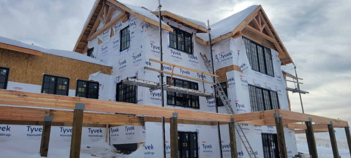 House under construction, exterior view with Tyvek wrap, snow on roof.