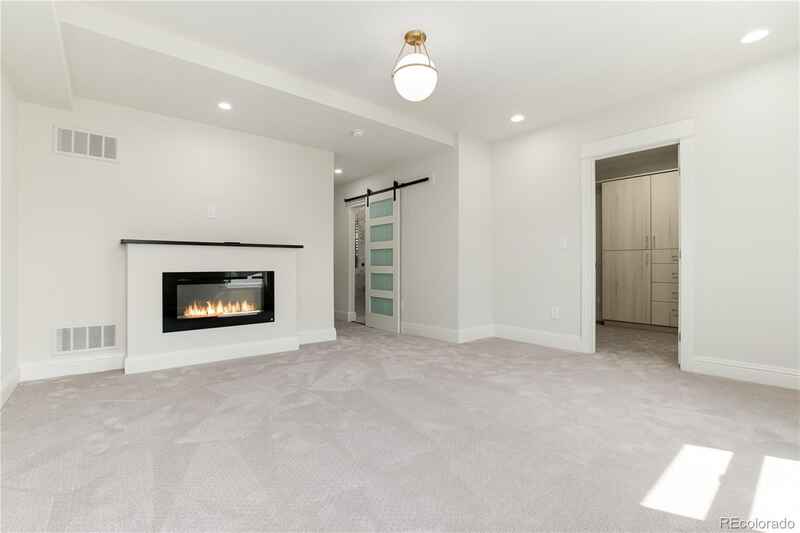 Spacious white bedroom with fireplace, closet entrance, and sliding glass door. Light gray carpet.